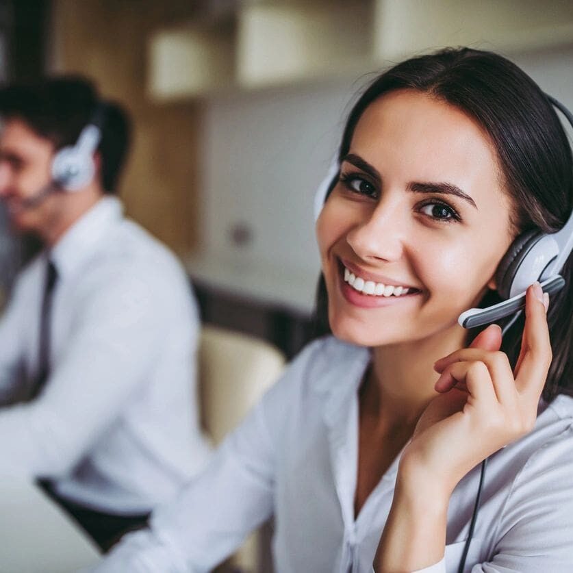 A woman is smiling while wearing headphones.